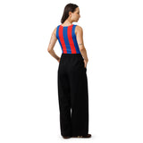 A woman shown from the back wearing a sleeveless top with bold vertical red and blue stripes and loose black wide-leg pants, photographed against a plain white studio background.